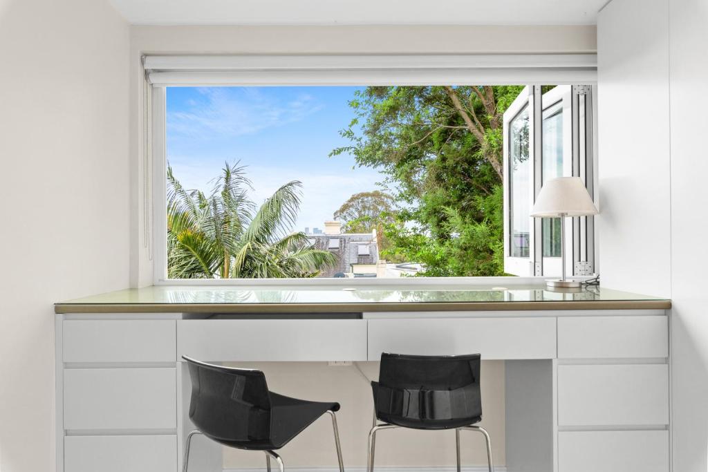 een keuken met een groot raam en 2 zwarte stoelen bij Elegant 1-Bed with Study by Balmain Wharf in Sydney