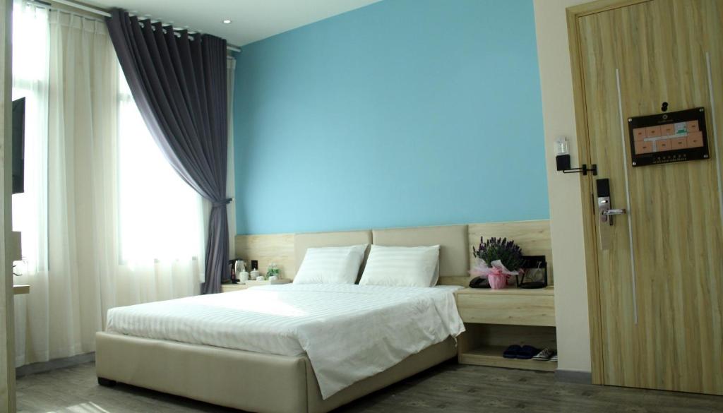 1 dormitorio con cama blanca y pared azul en Khách sạn Phước Lộc Thọ 2 - 福禄寿 en Ho Chi Minh