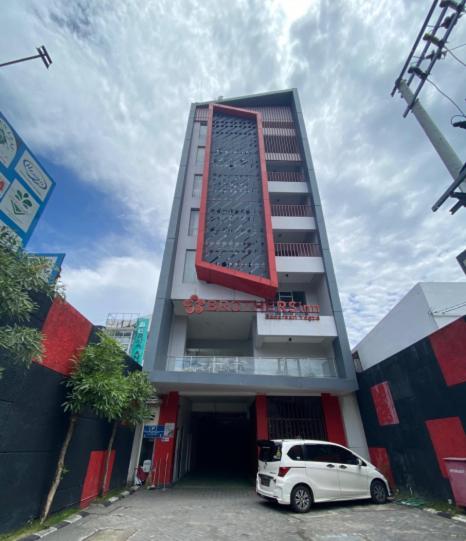 a white car parked in front of a tall building at Brothers Inn Babarsari in Yogyakarta
