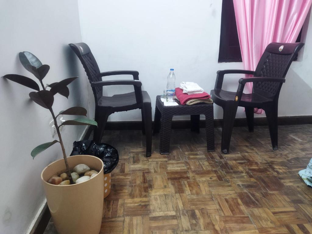 une chambre avec trois chaises, une table et une plante en pot dans l'établissement Samarpan stay, à Nainital