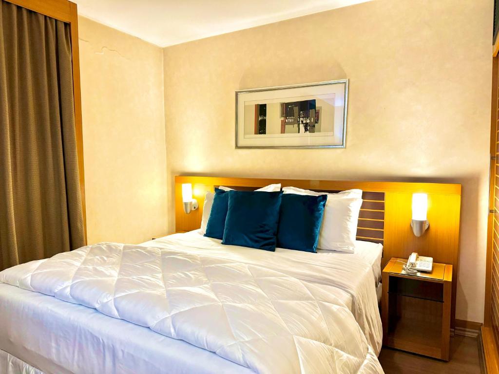- une chambre avec un grand lit et des oreillers bleus dans l'établissement Hotel - São Paulo AV Paulista, à São Paulo