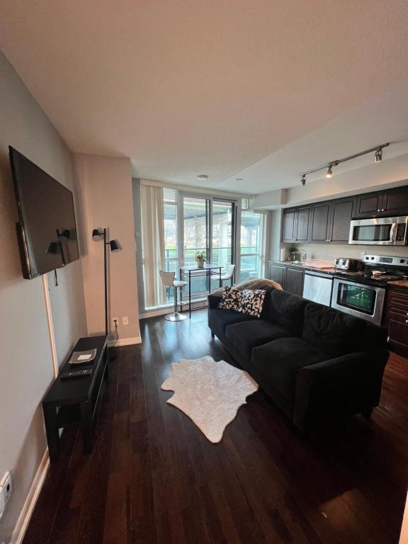 a living room with a black couch and a kitchen at Downtown Toronto Cozy Suite in Toronto