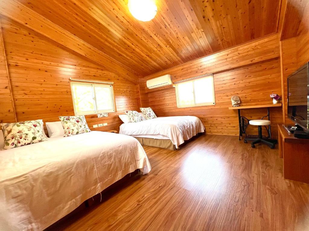 a bedroom with two beds in a wooden cabin at Annongriver B&amp;B in Sanxing