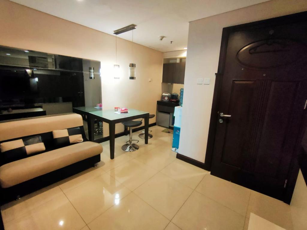 a living room with a table and a chair and a door at eL Royale Apartment by Faris Property in Bandung