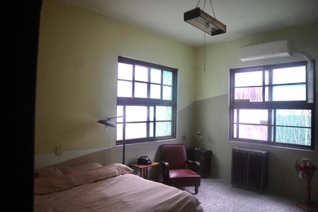 sypialnia z 2 oknami, łóżkiem i krzesłem w obiekcie Everythingsoup w mieście Zhangua