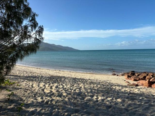 a sandy beach with rocks and the ocean at Hideaway Reef Cottage in Hideaway Bay