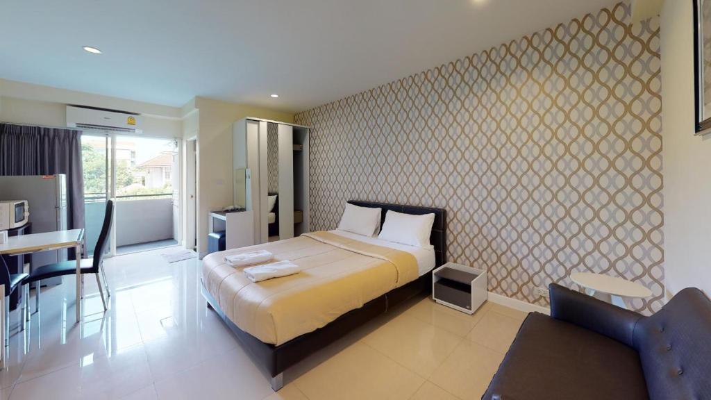 a bedroom with a bed and a table and a chair at The Arni Sukhumvit 101 in Bangkok