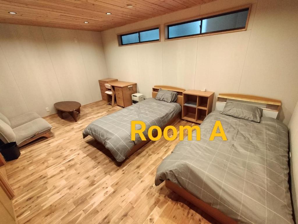 een kamer met 2 bedden en een stoel. bij Long Stay Takayama in Takayama
