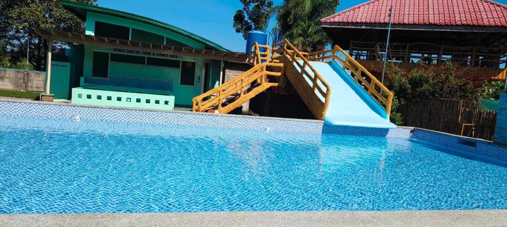 a slide in a swimming pool next to a house at Arzel's Tiny House in Mangatarem