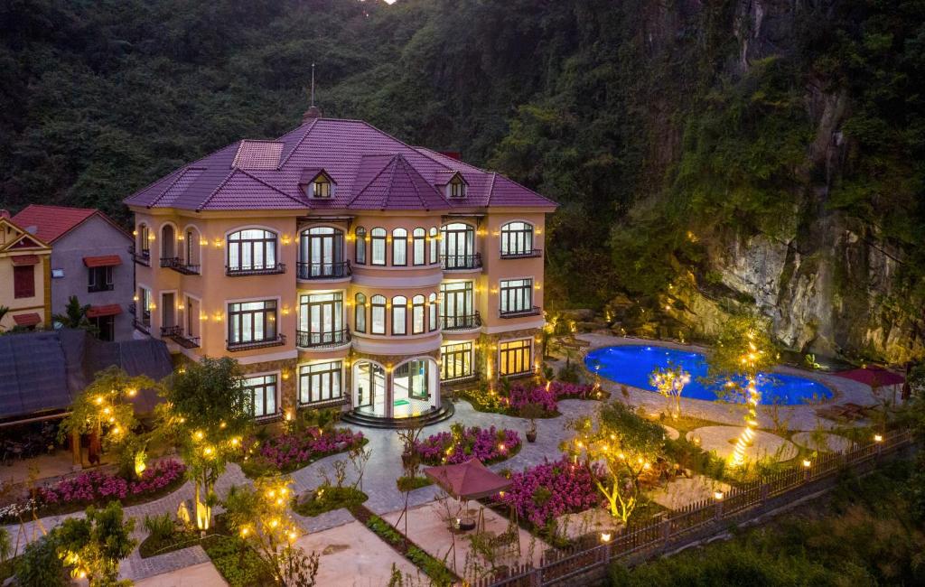 ニンビンにあるIndochine Boutique Hotel Ninh Bìnhの山の前にプールがある大きな建物