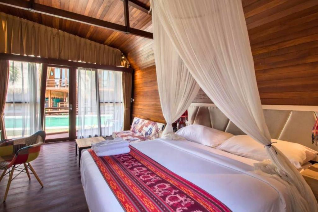 a bedroom with a large bed with a canopy at Ammora 1 BR Deluxe Suite NE60 in Gili Air