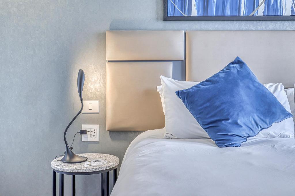 Una cama con una almohada azul y una lámpara sobre una mesa en The Capital in Sandton, en Johannesburgo