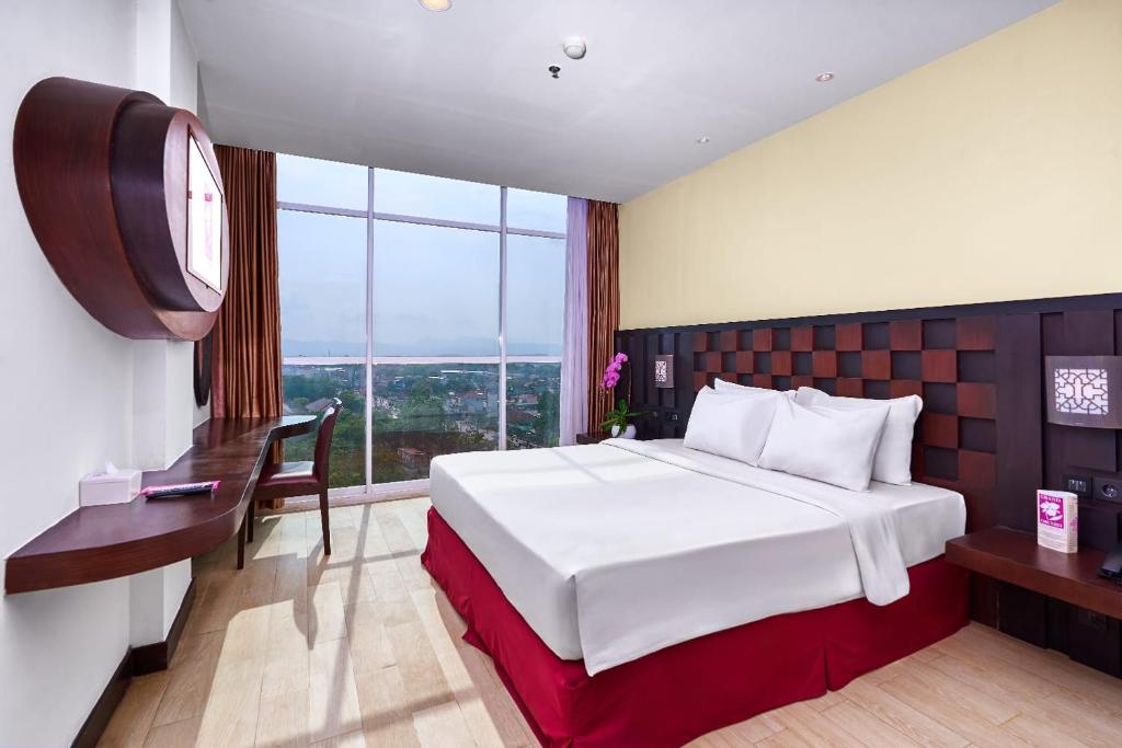 ein Hotelzimmer mit einem großen Bett und einem Fenster in der Unterkunft Grand Orchid Hotel Yogyakarta in Yogyakarta