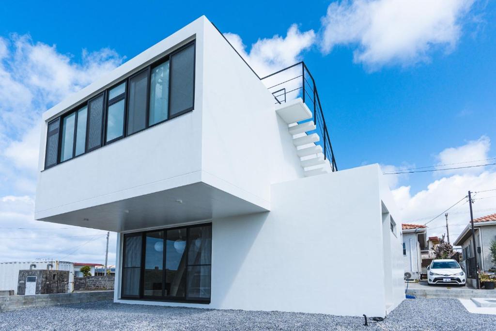 uma casa branca com escadas ao lado em Nashiro White Cube - Vacation STAY 14460 em Itoman