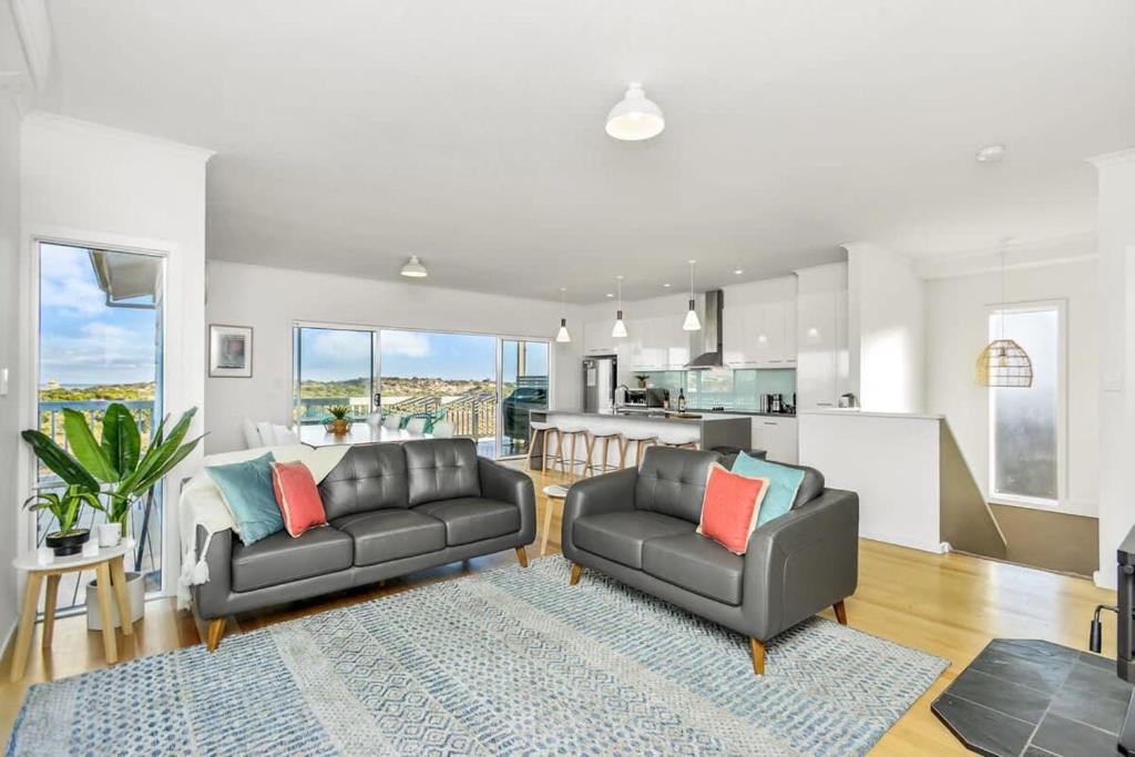 a living room with two couches and a kitchen at Dunescape - Coastal Serenity with Fire & Views in Goolwa South