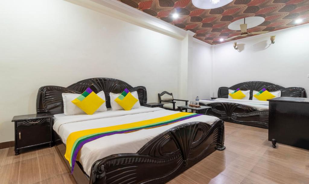 1 dormitorio con 2 camas y almohadas coloridas en Itsy By Treebo - Paradise Inn, Haridwar, en Haridwar