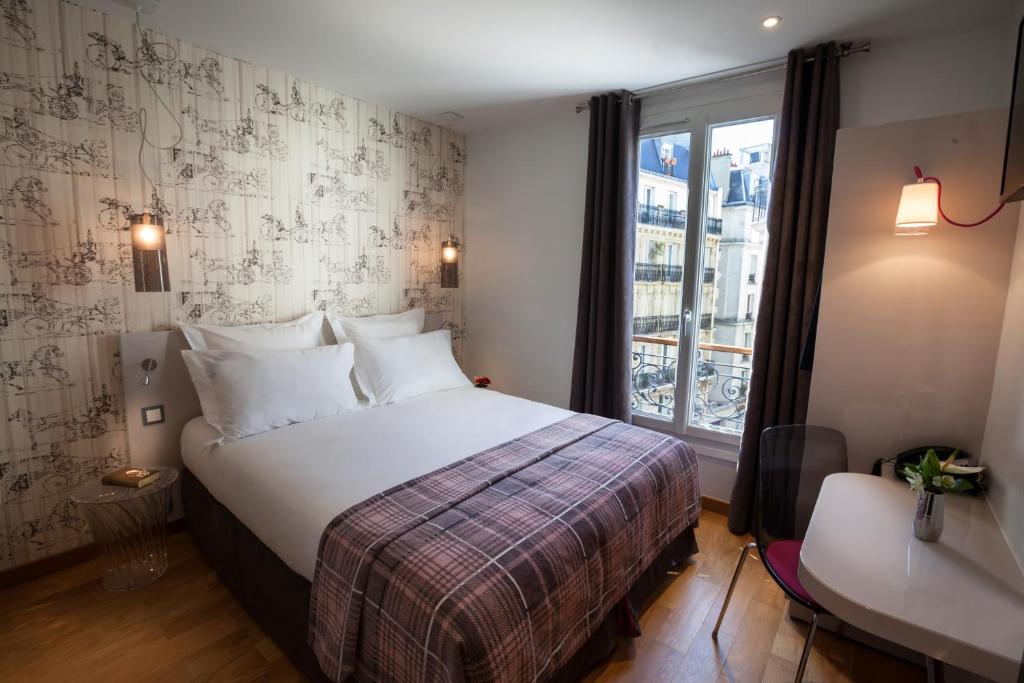 une chambre d'hôtel avec un lit et une fenêtre dans l'établissement Le Mireille, à Paris