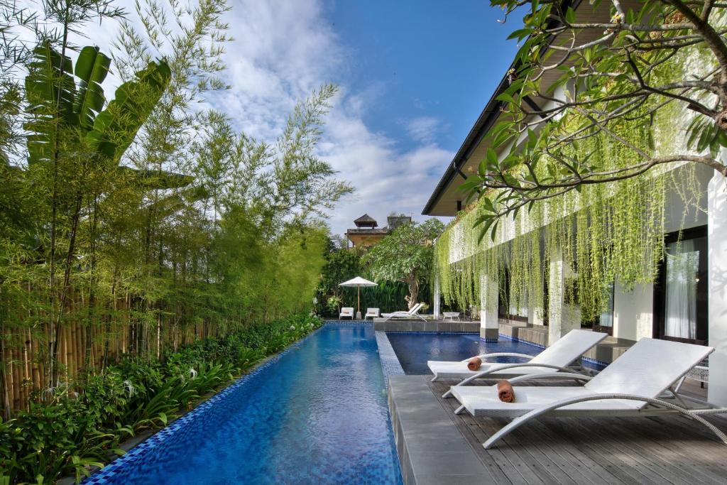 a pool with lounge chairs next to a building at AmantraNa Canggu in Canggu