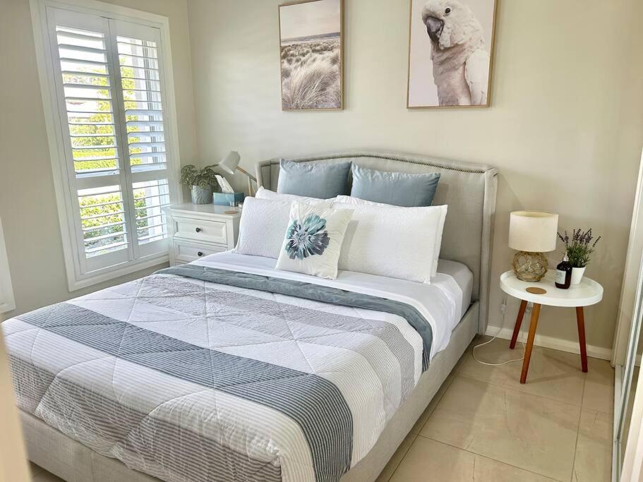a bedroom with a bed with a blue and white comforter at Guest house in Harrington Park in Narellan
