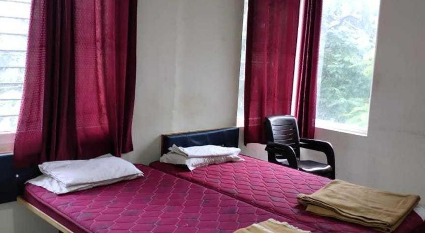 1 dormitorio con cama morada y cortinas rojas en hotel kings, en Gulbarga