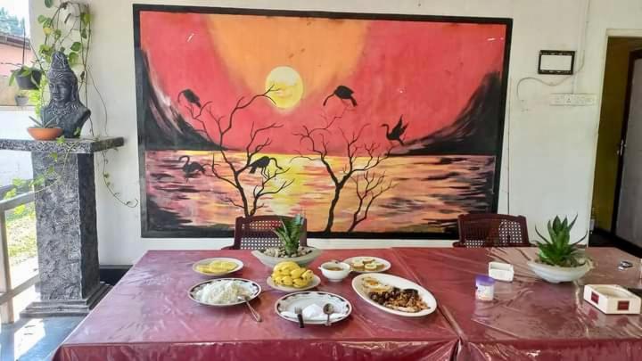 una mesa roja con comida en ella con una pintura en River Paradise en Kalutara