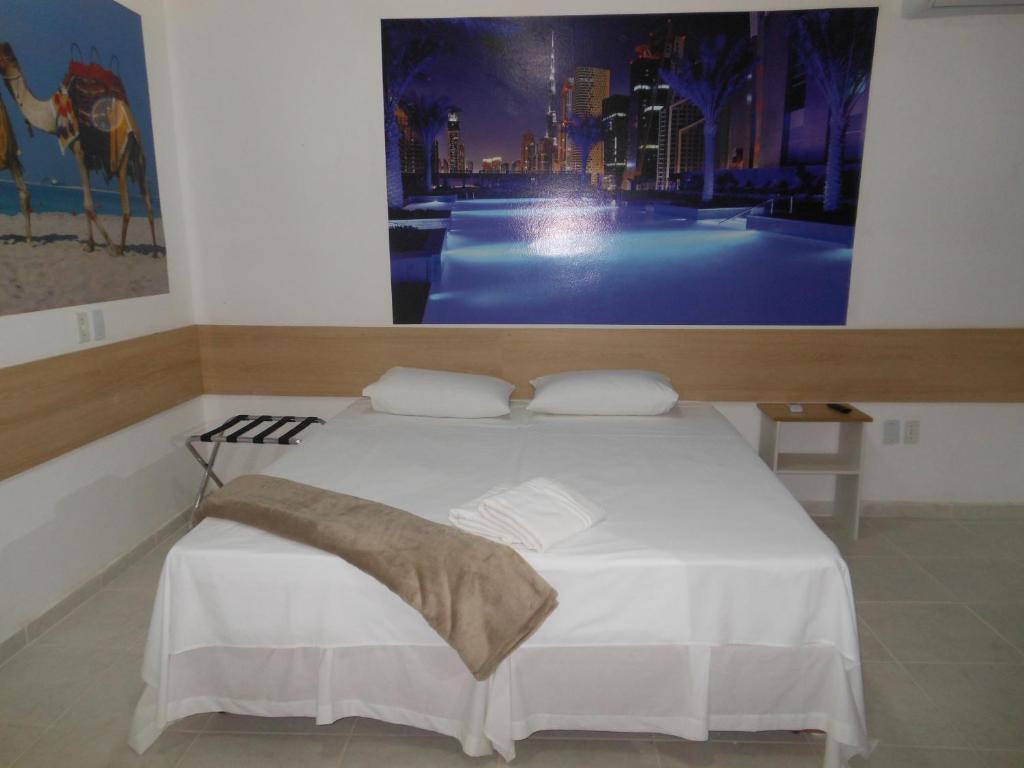 una camera con un letto bianco e una foto appesa al muro di Pousada Dubai a Taubaté