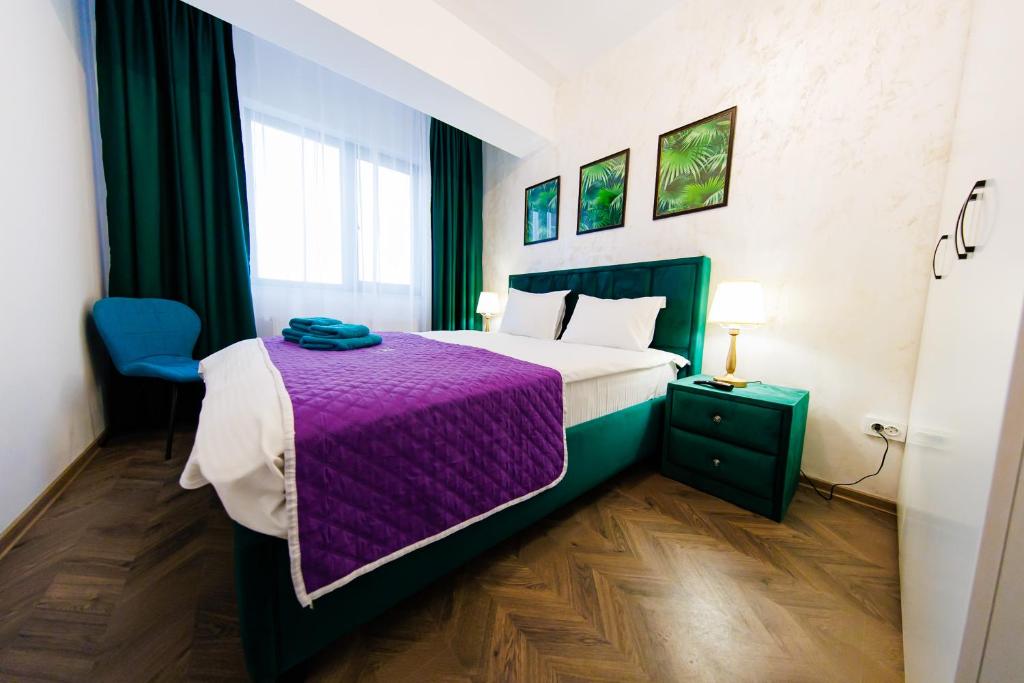 um quarto com uma cama grande e um cobertor roxo em Luxury Lazar Towers Palas Mall Area em Iaşi