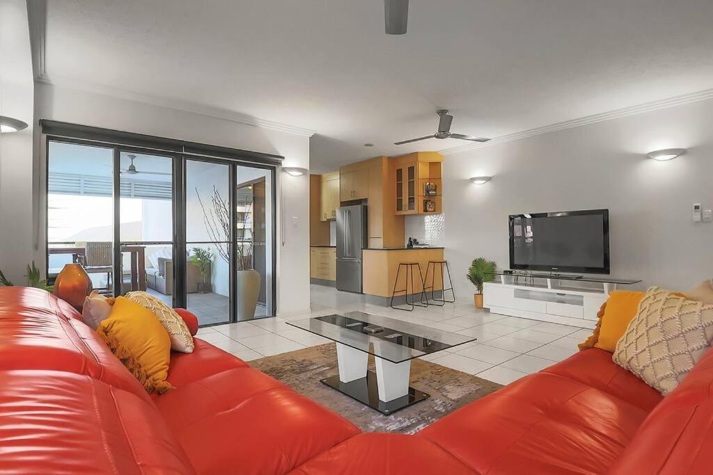 a living room with a red couch and a television at An abode on Abbott - In the heart of the city in Cairns