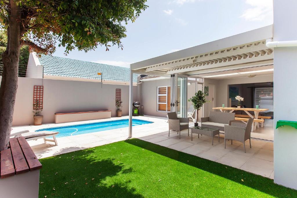 a backyard with a pool and a table and chairs at 17A Raven Street Vacation Home in Bloubergstrand