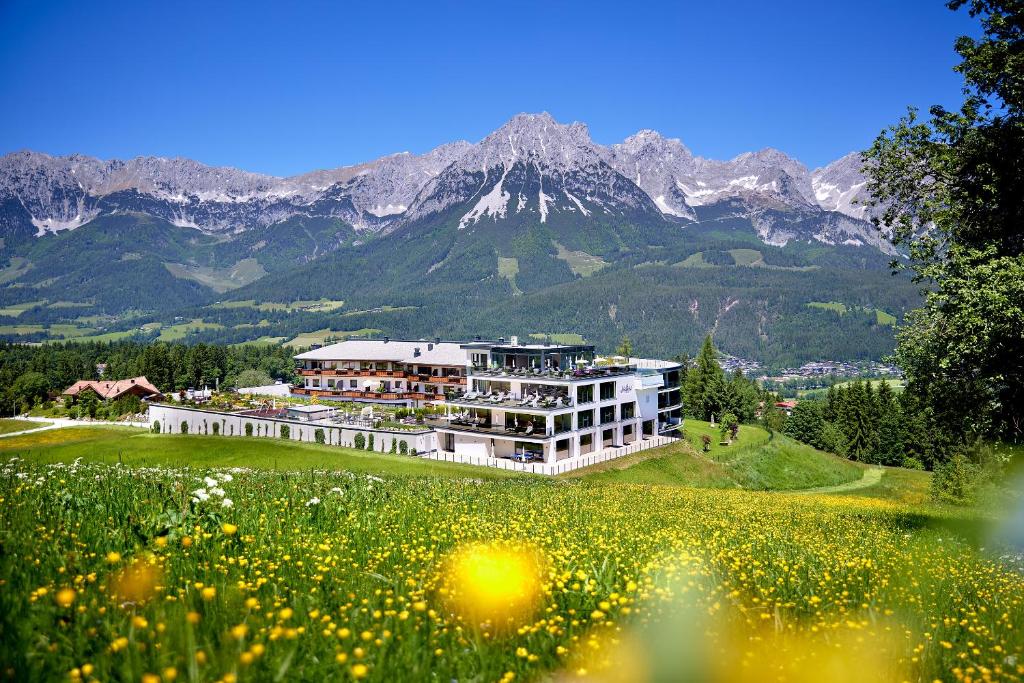 a building on a hill with a field of flowers at Kaiserhof Superior in Ellmau