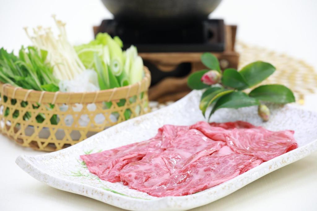 a plate of meat next to a basket of vegetables at Hotel Binario Saga Arashiyama in Kyoto