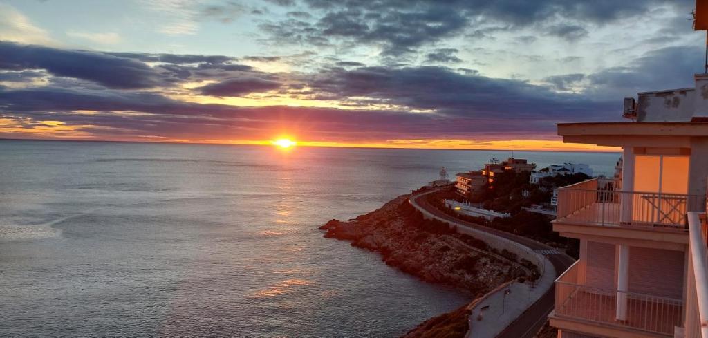 - un coucher de soleil sur l'océan avec des bâtiments et l'océan dans l'établissement Amazing Seaviews in Faro de Cullera, à Faro de Cullera