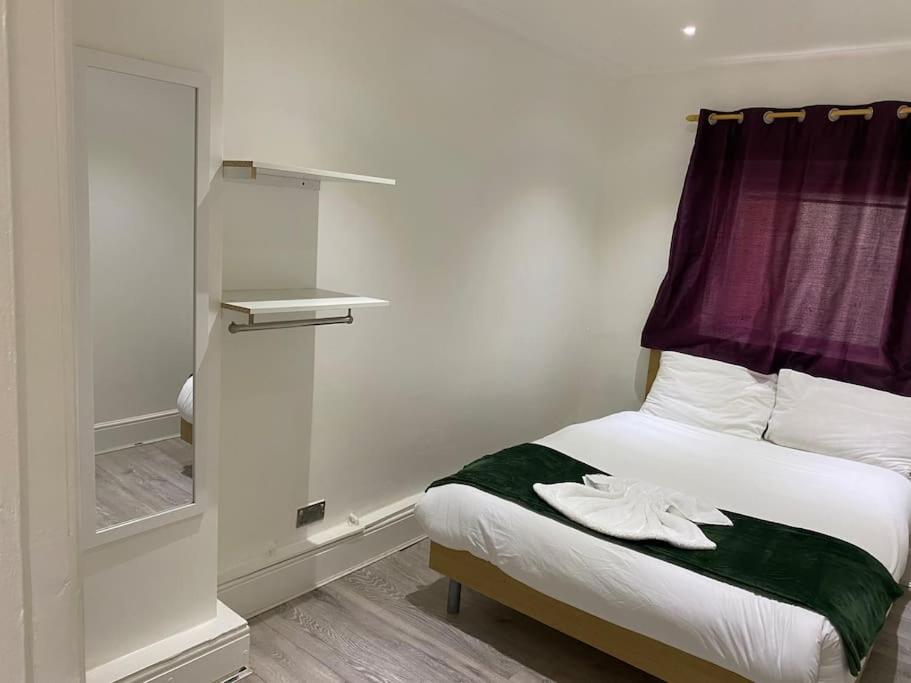 1 dormitorio con 1 cama con cortina y ventana en The w3 flat en Londres