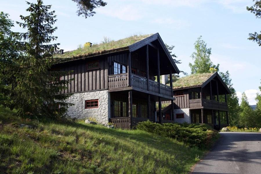 une grande maison en bois avec un toit en gambrel dans l'établissement Hunderfossen Apartments, à Hafjell