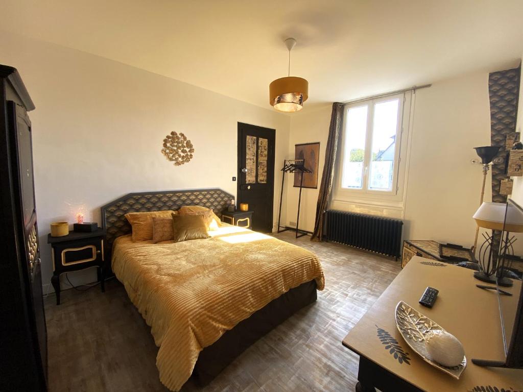 a bedroom with a large bed and a desk at Chambre dorée in Pleurtuit