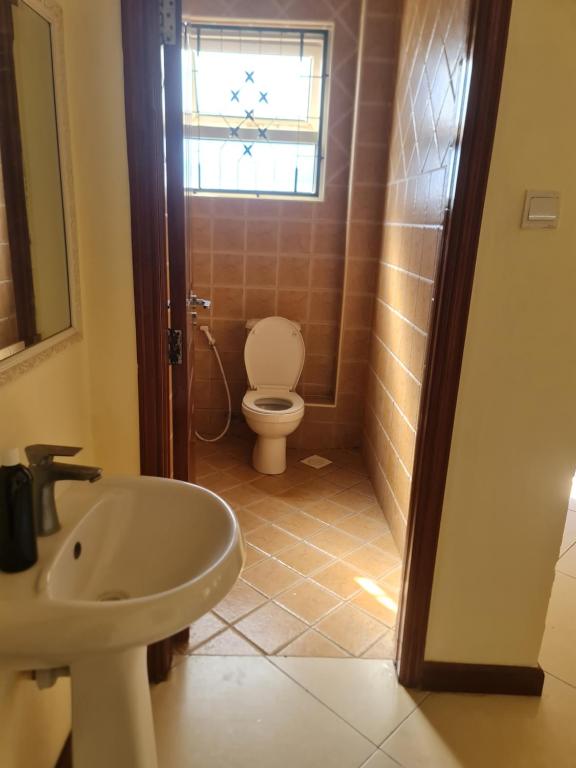 a bathroom with a toilet and a sink and a window at Flix holdings- Apa apartments mombasa in Mombasa