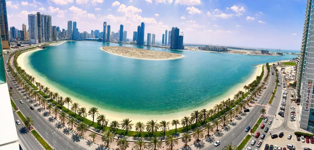 a large body of water with palm trees and a city at Luxury Apartment Al Khan Corniche View 2 BD in Sharjah