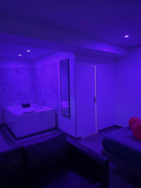 fioletowy pokój z wanną i lustrem w obiekcie Lov’SPA 2 w mieście Fleury-Mérogis
