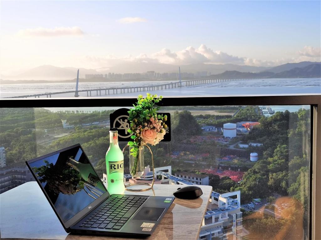 um computador portátil sentado numa mesa com uma garrafa de vinho em Interact China Fine Condo - Shenzhen Bay em Shenzhen