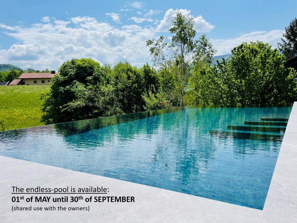 a large pool of water with trees in the background at place2be - with infinity pool in Faistenau