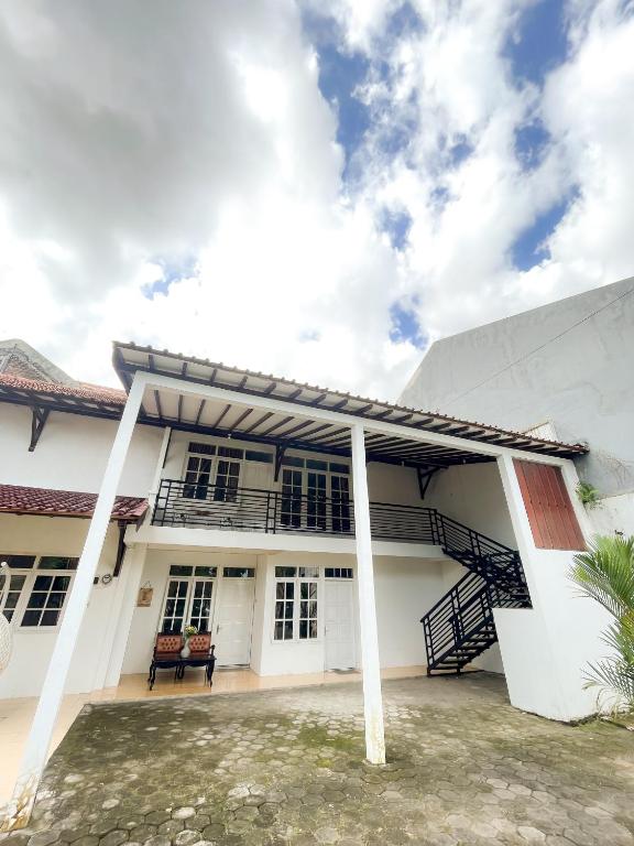 uma casa branca com uma escada em frente em Villa Kamar Tamu Ngestiharjo em Jetis