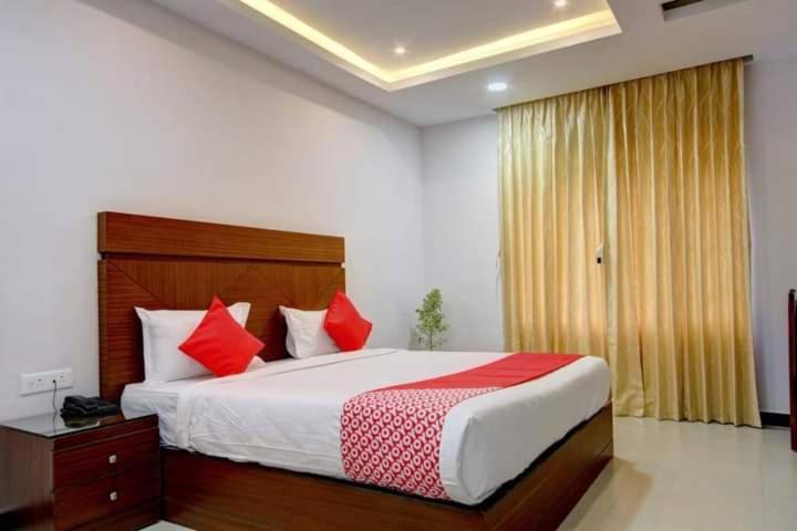 um quarto com uma cama grande e almofadas vermelhas em Hotel Le Castle em Kodaikanal