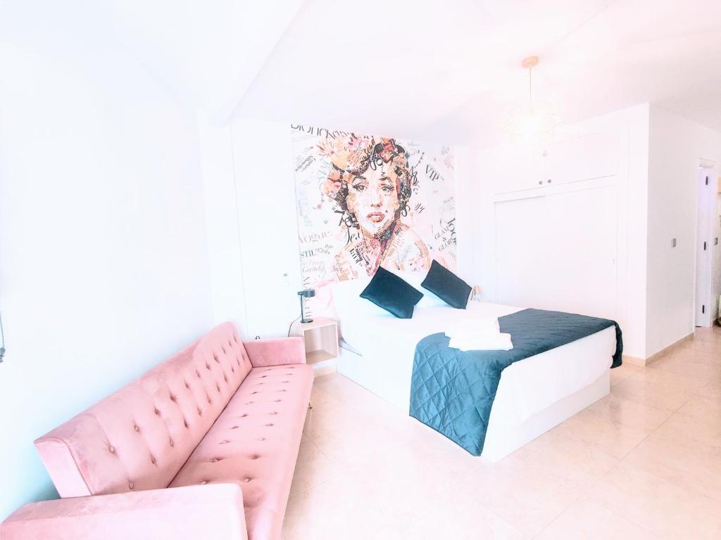 ein Schlafzimmer mit einem Bett und einem Sofa und einem Wandbild in der Unterkunft Golden Estudio in Málaga