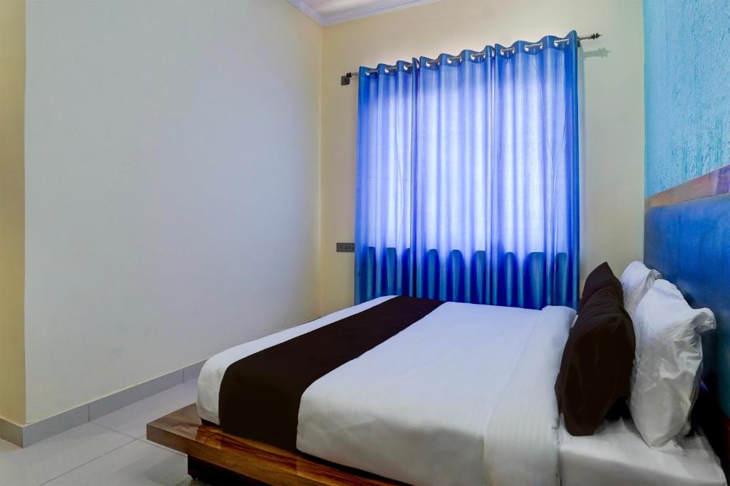 OYO HOTEL STAY INN في هالدوانى: غرفة نوم بسرير وستارة زرقاء