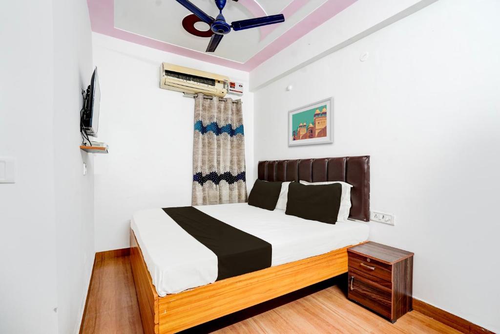 OYO Premier Jim Corbett Home Stay في رامناجار: غرفة نوم بسرير ومروحة سقف