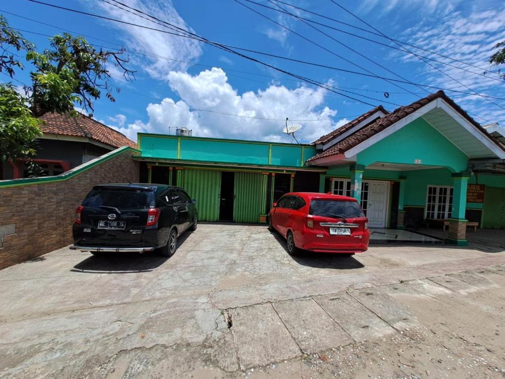 deux voitures garées devant une maison dans l'établissement OYO 93814 Amanda Homestay, à Bandar Lampung