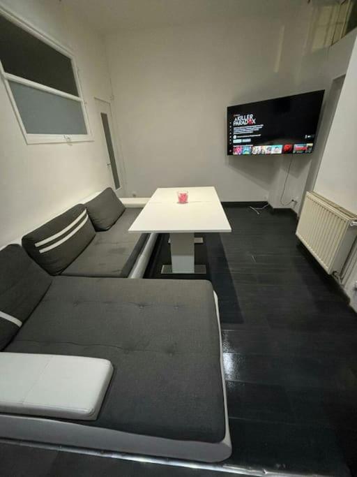 een kamer met een bank, een tafel en een tv bij Authenticité au cœur de la ville in Lyon