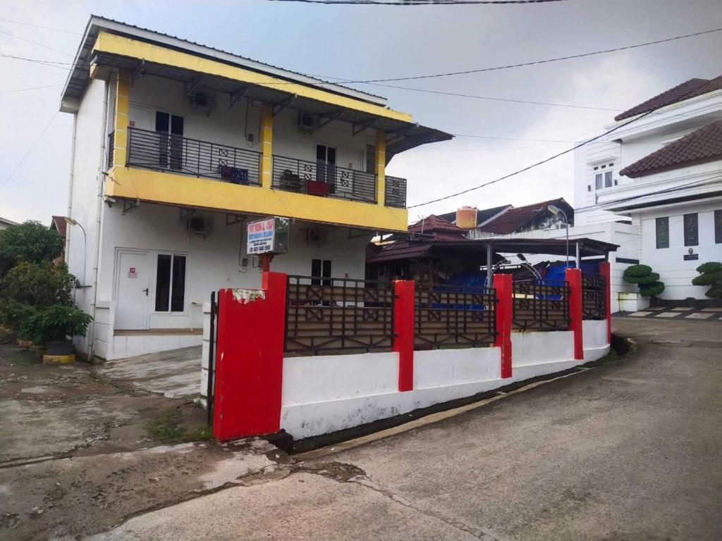 un edificio con una valla roja delante de él en OYO 93818 Wisma Al Araf Syariah, en Palembang
