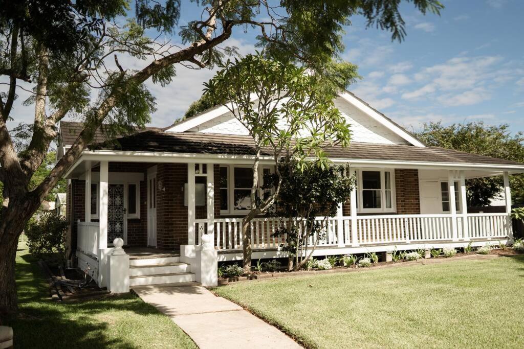une maison blanche avec une terrasse couverte et une pelouse dans l'établissement The Whitehouse on Boyce Street, à Taree