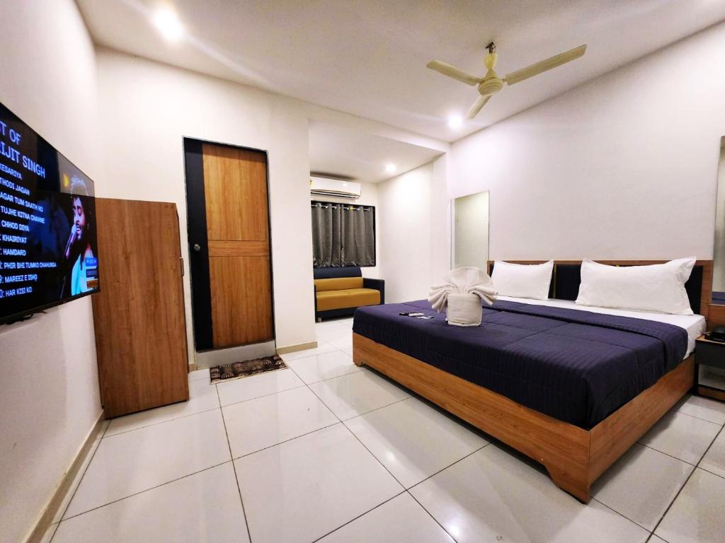 um quarto com uma cama e uma televisão em Hotel Near Me em Rajkot